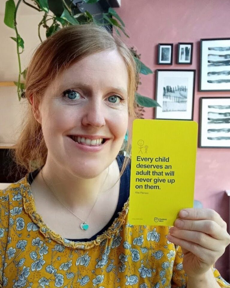 Collette Costello, The Dyslexic Mum and creator of Mooki Cards, smiling and holding a yellow card