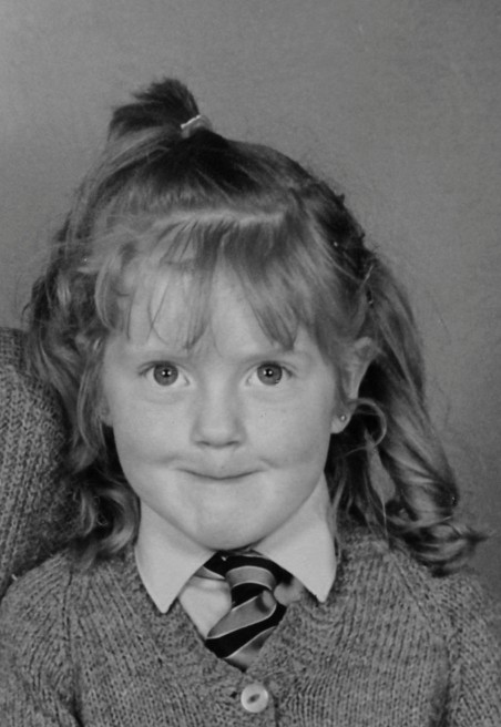 Collette Costello as a young girl in her school photo, in a cardigan and striped school tie